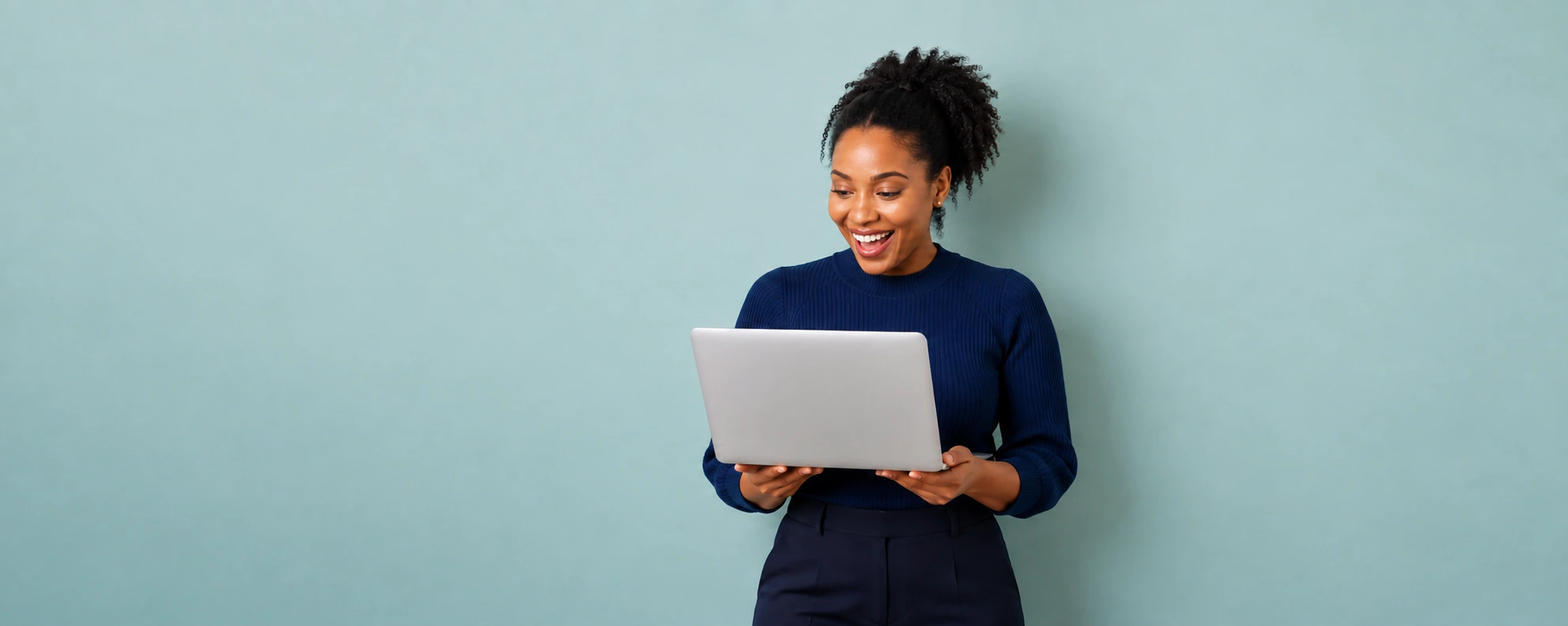 Woman smiling while holding a laptop against a soft blue-green background